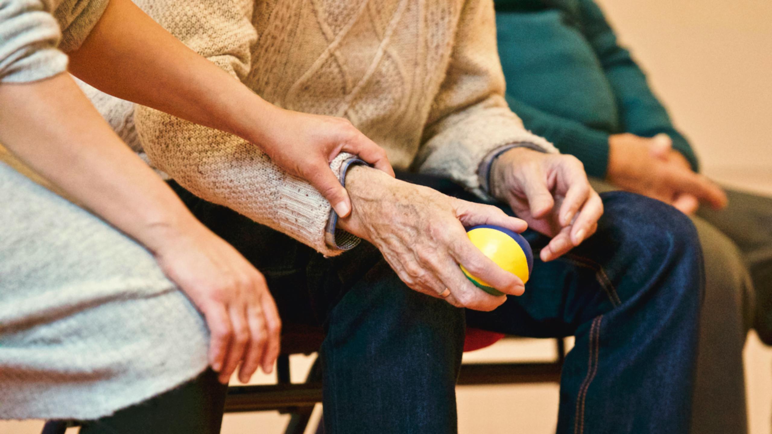 NDIS service provider holds arm of elderly participant.